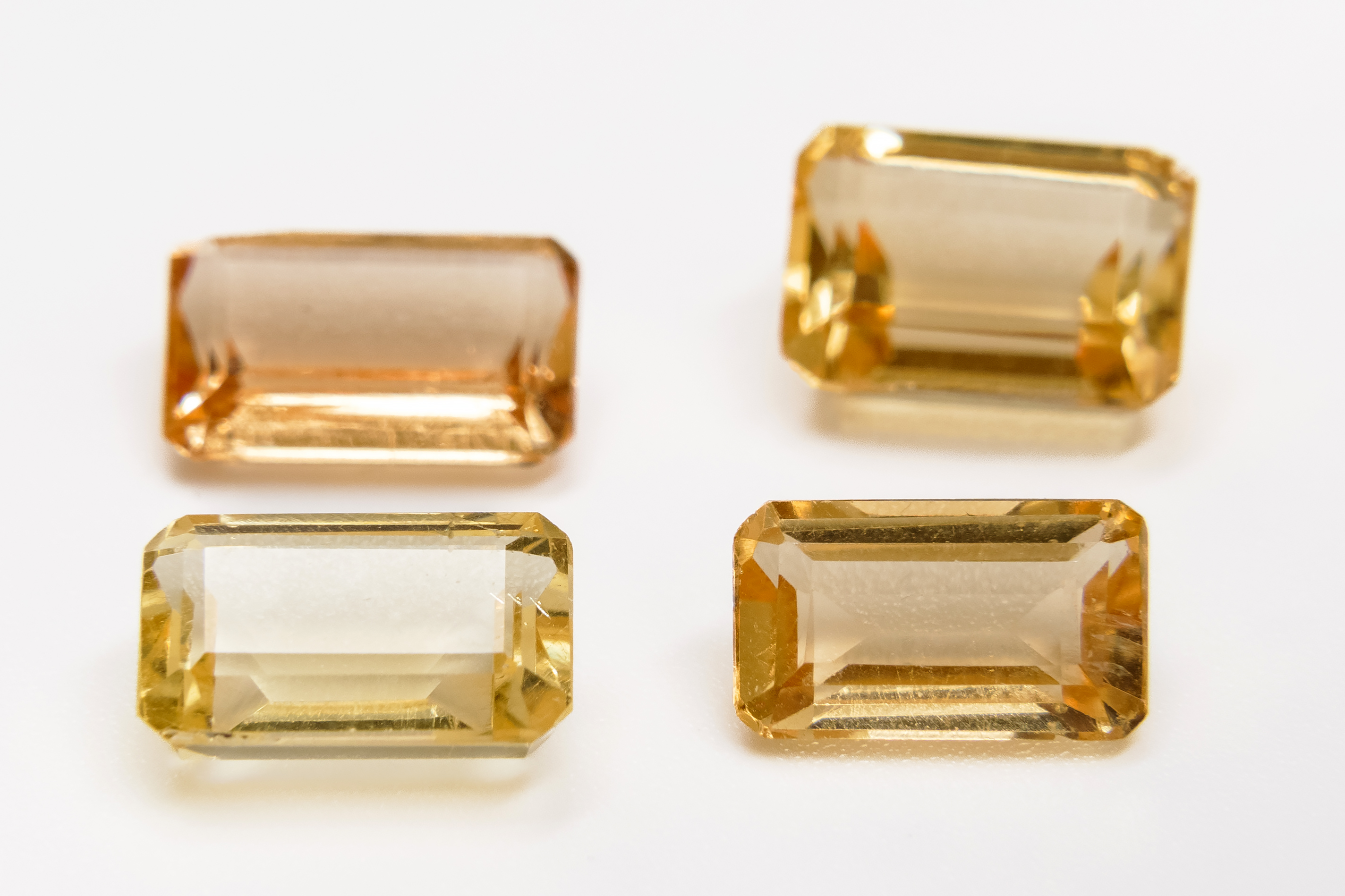 Four golden-yellow emerald-cut beryl gems, some with pale windows.