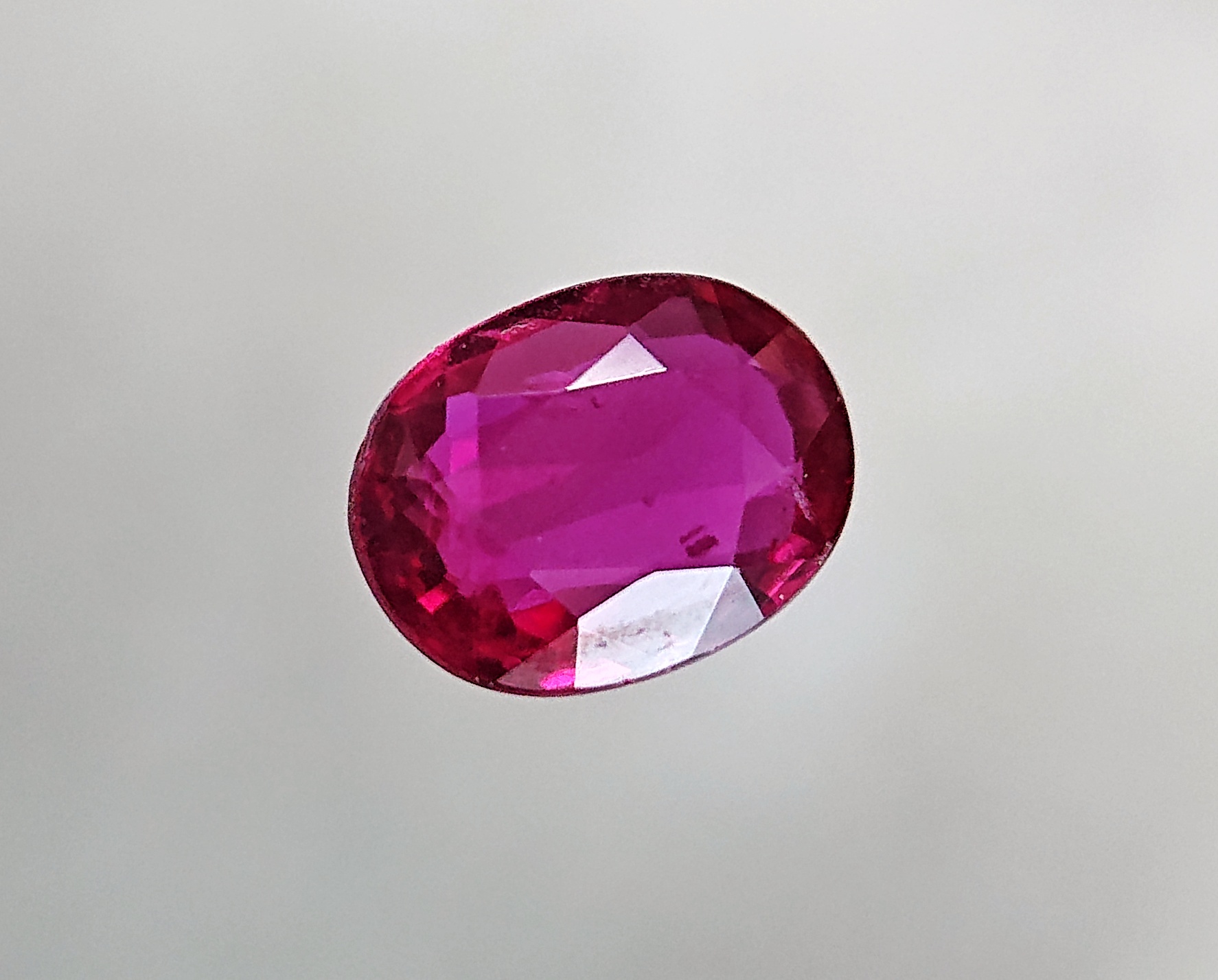 A single oval faceted pink-red ruby.