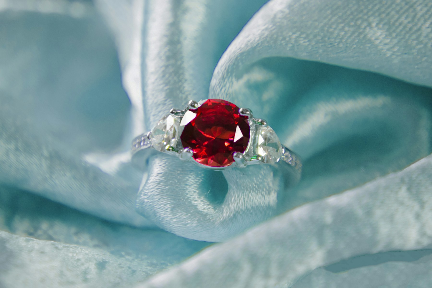 A ring with a round red center stone on pale blue silk.