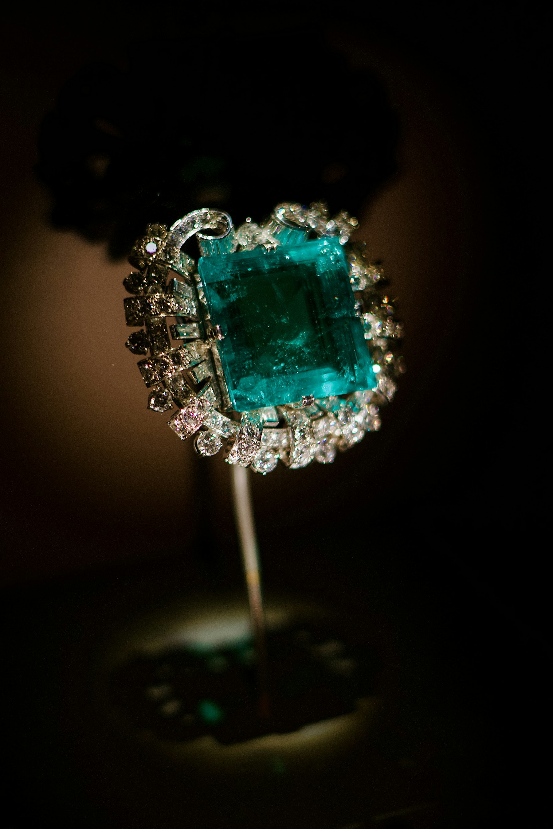 A large emerald-cut green stone in a diamond mounting.