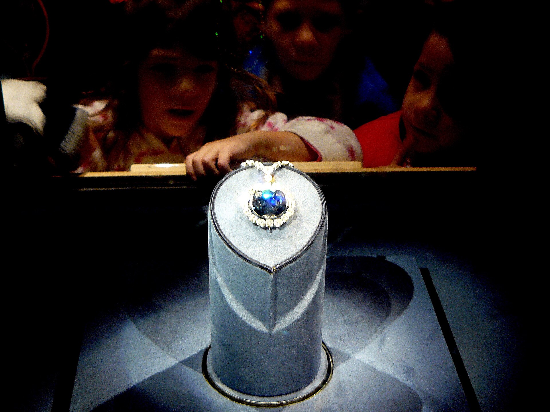 Visitors leaning over a museum case to look at the Hope Diamond.
