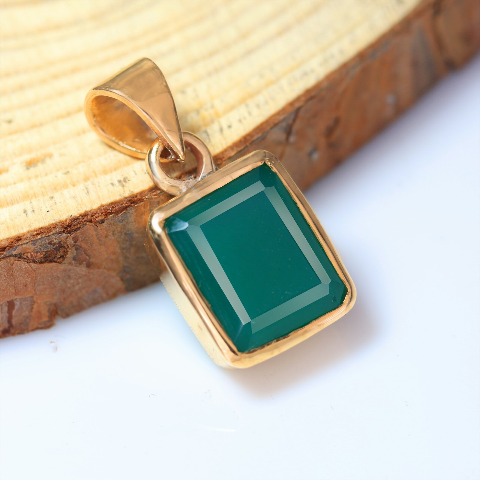 A flat green stone in a plain gold bezel.
