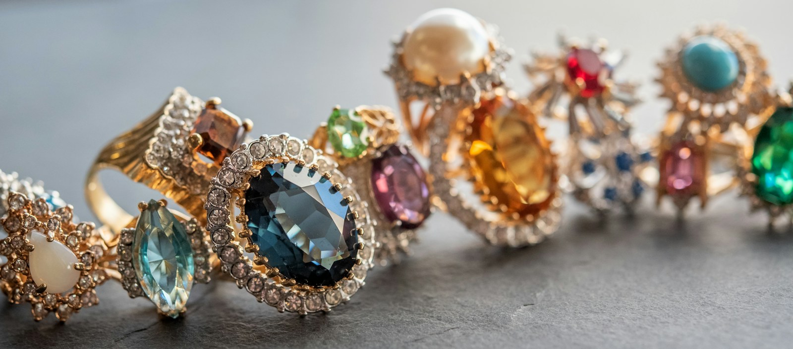 A row of gold rings set with blue, green, purple, orange, and red stones.