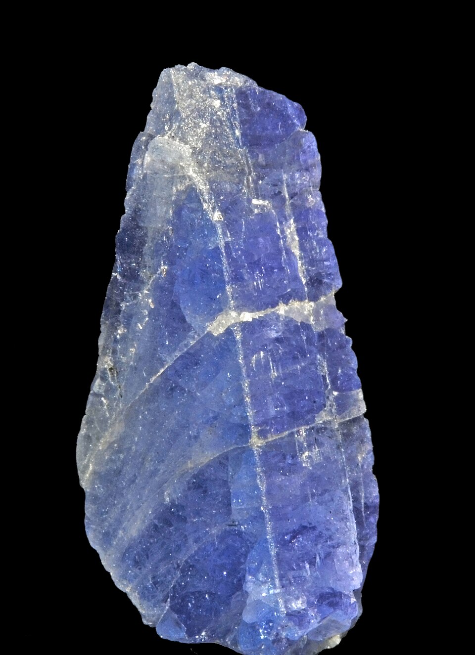 A rough blue-violet tanzanite crystal on a black background.
