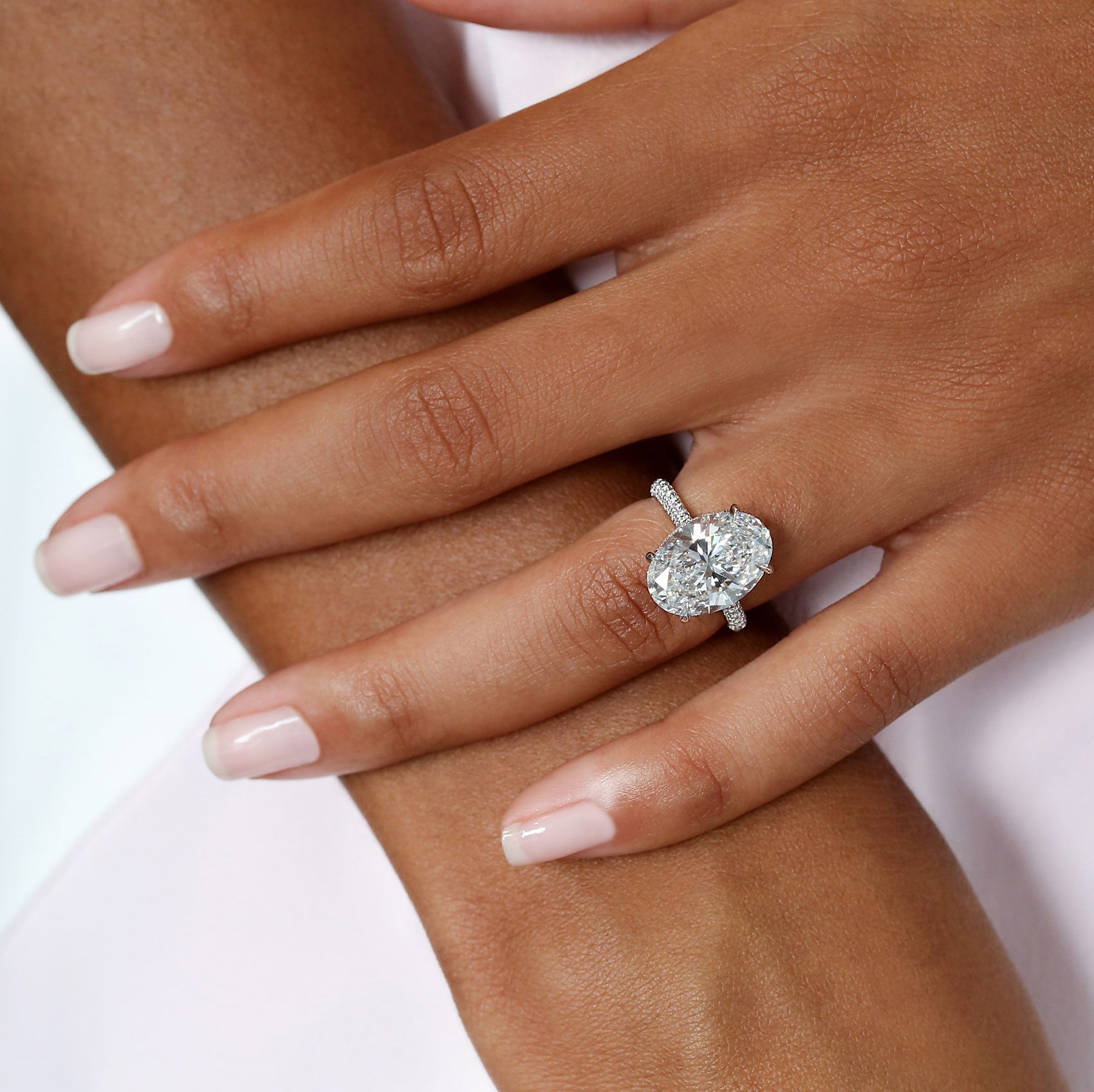 An oval brilliant diamond in a pavé ring on a hand.