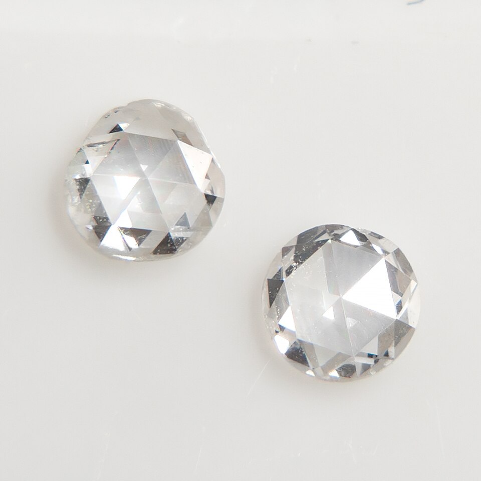 Two flat rose-cut diamonds on a light surface.