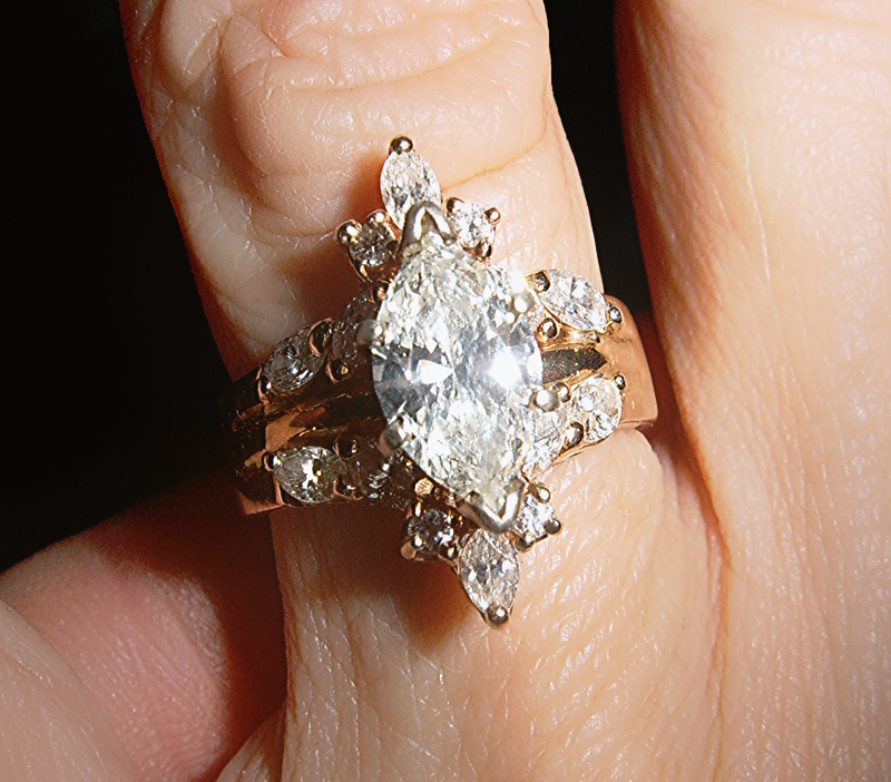 A gold ring with a large marquise diamond and smaller marquise stones around it.