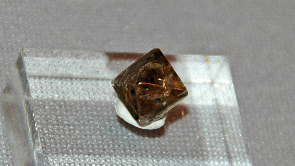 A brown octahedral diamond crystal on a small stand.