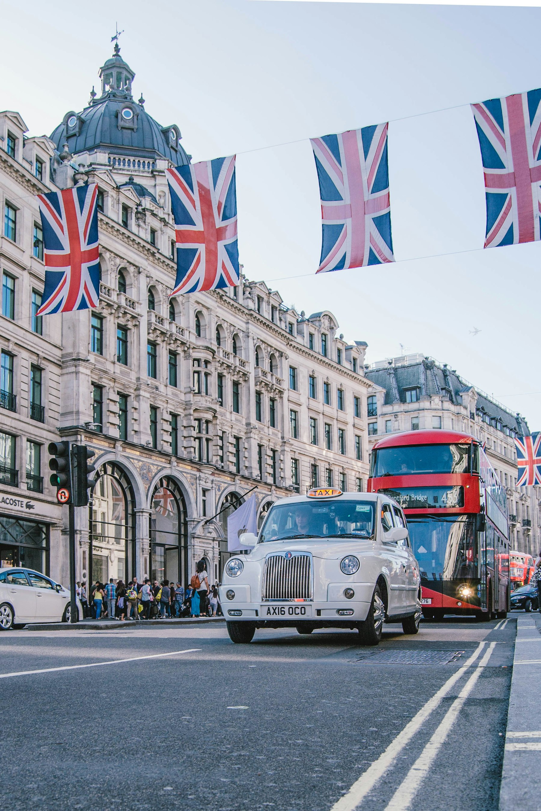 A London street with a taxi, a red bus, and Union Jack flags.