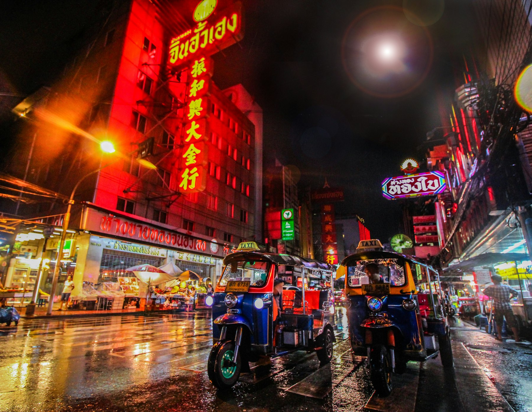 Tuk-tuks on a rainy night street in Bangkok.