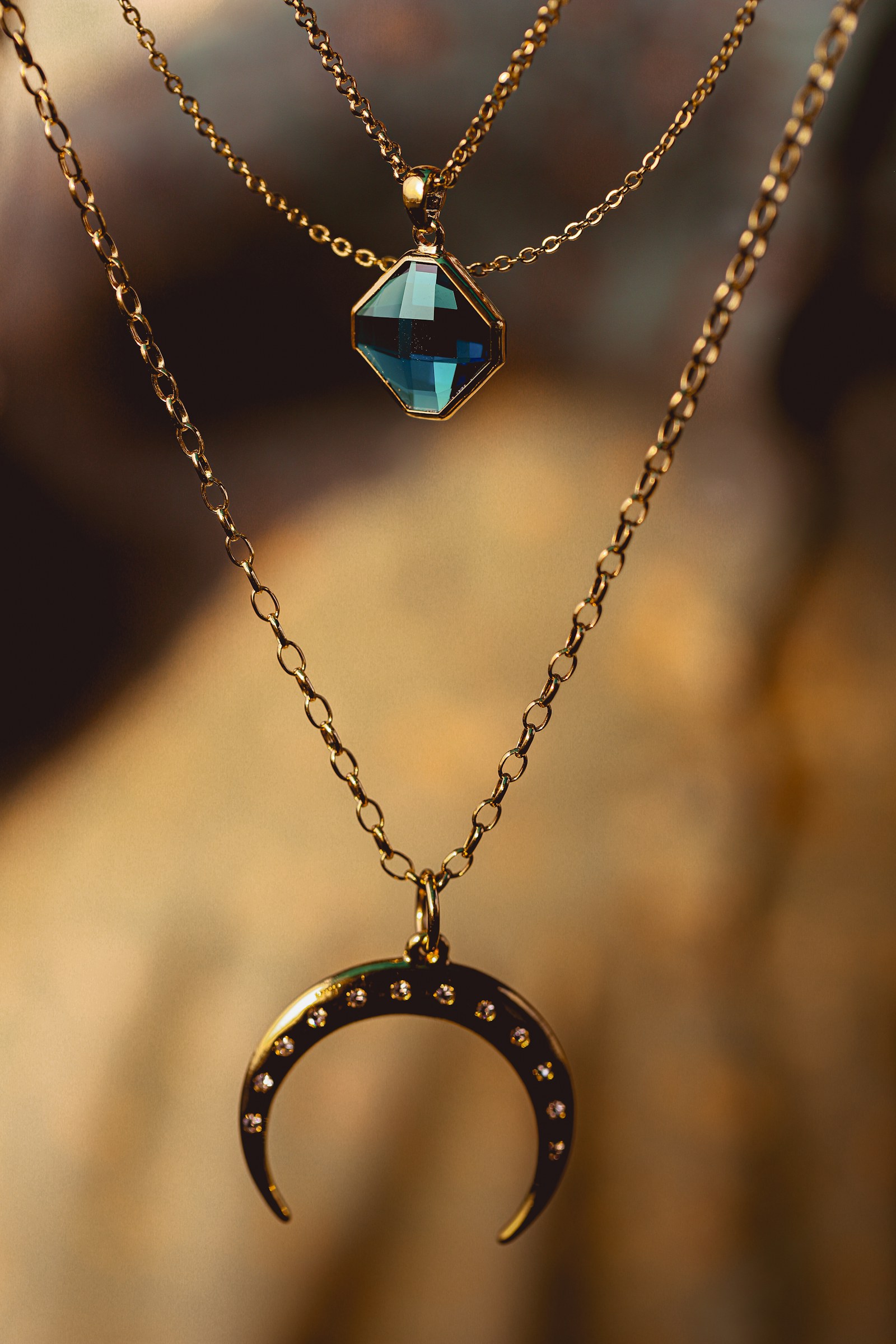 Layered gold chains with a small blue stone.